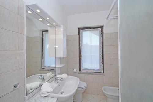 ein Badezimmer mit einem Waschbecken, einem WC und einem Spiegel in der Unterkunft Lina's Apartment - Gardagate in Moniga