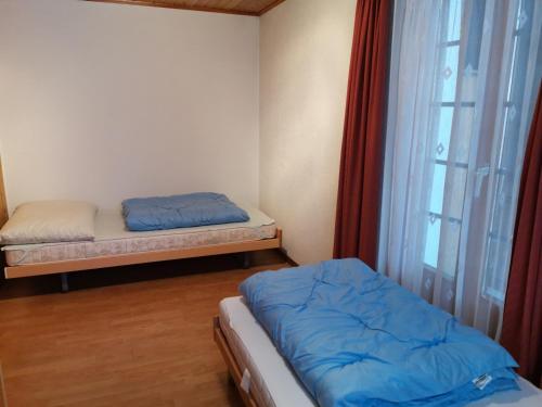 Habitación pequeña con 2 camas y ventana en Imseng, en Wiler