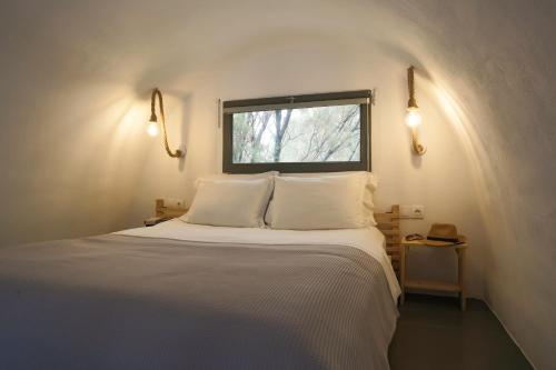 una camera da letto con un letto con lenzuola bianche e una finestra di Exi Sea Side Suites a Perissa