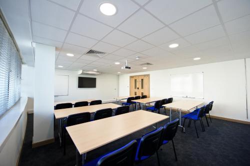 a conference room with tables and chairs and a screen at Staycity Aparthotels Manchester Piccadilly in Manchester