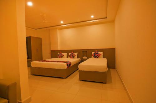 a room with two beds and a chair in it at FabHotel Champion Gateway - Yelahanka in Bengaluru