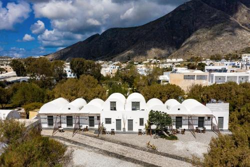 a white building with a mountain in the background at Exi Sea Side Suites in Perissa