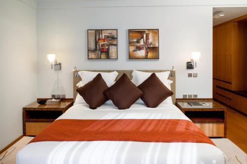 a bedroom with a large bed with three paintings on the wall at InterContinental Al Khobar by IHG in Al Khobar