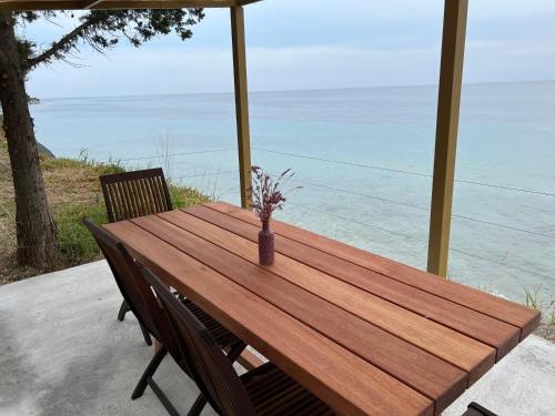 a wooden table with chairs and a vase with flowers at iHouse Nea Skioni in Nea Skioni