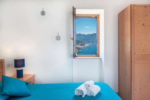 a bedroom with a bed and a window with towels at La Sciuscella in Conca dei Marini