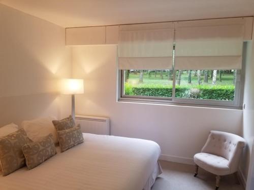 1 dormitorio con cama, ventana y silla en Deauville vue mer en Tourgeville
