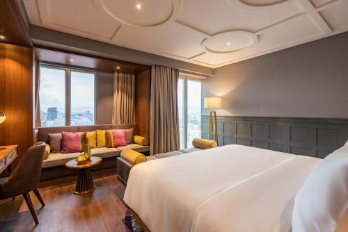 ein Hotelzimmer mit einem großen Bett und einem Sofa in der Unterkunft Fusion Original Saigon Centre in Ho-Chi-Minh-Stadt