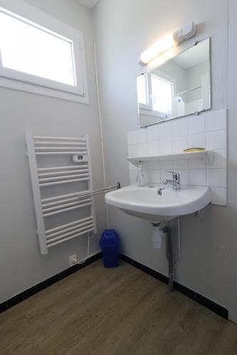 une salle de bain blanche avec un lavabo et un miroir dans l'établissement Une grande maison pour 10 proche de la mer, à Saint-Gilles-Croix-de-Vie