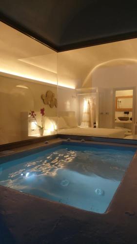 a large swimming pool in a room with a bed at Kaleidoscope Imerovigli Suites in Imerovigli