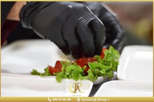 a hand in a black glove holding a plate of vegetables at Ureni Hotel in Kʼasakh