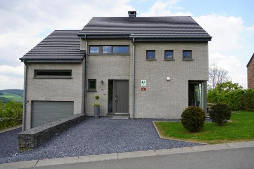a brick house with a garage on a driveway at "Petite perle en Haute Ardenne" avec vue sur la vallée, cabine infra-rouge et bain balnéo in Lierneux