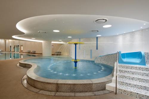 a swimming pool with an umbrella in a building at Lotte Hotel World in Seoul