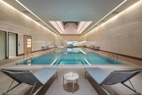 a large swimming pool with chairs and a table in a building at Lotte Hotel World in Seoul