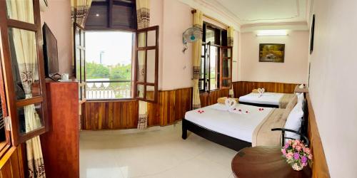 a room with two beds and a window at Nam Phương Riverside Villa in Hue