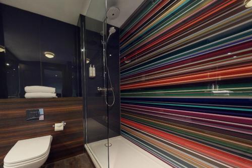 a colorful wall in a bathroom with a toilet at Village Hotel Chester St David's in Garden City