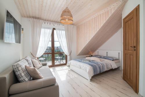 a bedroom with a bed and a couch and a window at Zielone Miejsce - w otoczeniu natury, z balią z jacuzzi opalaną drewnem in Karwia