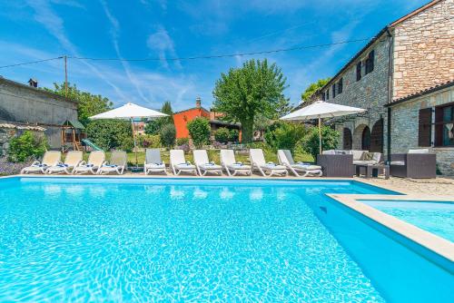 a pool with chairs and umbrellas next to a building at Villa Murva in Žminj