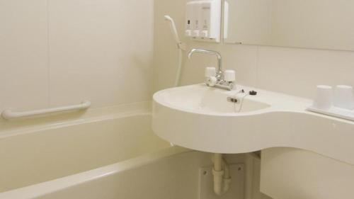 a white bathroom with a sink and a bath tub at Toyoko Inn Shonan Chigasaki eki Kita guchi in Chigasaki
