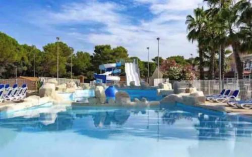 a swimming pool with chairs and a water slide at Bungalow de luxe de 60m2 dans camping 5 étoiles in Puget-sur Argens
