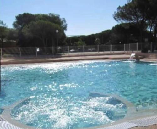 a swimming pool with blue water in a park at Bungalow de luxe de 60m2 dans camping 5 étoiles in Puget-sur Argens