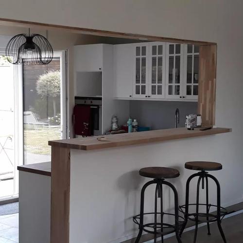 une cuisine avec des placards blancs et deux tabourets de bar dans l'établissement Chez Stephane et Sylvie, au Mans