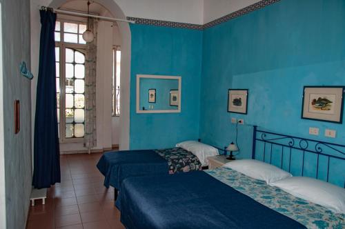 two beds in a room with blue walls at Hotel Villa Morgana in Viareggio