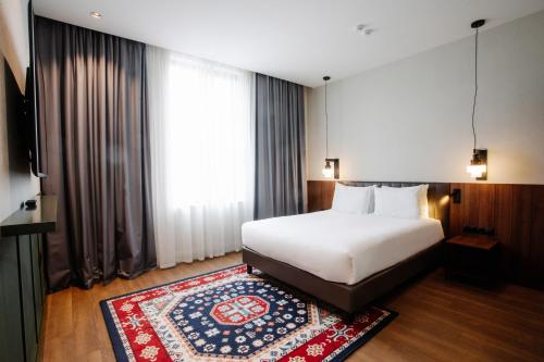 a hotel room with a bed and a rug at Holiday Inn Telavi by IHG in Tʼelavi