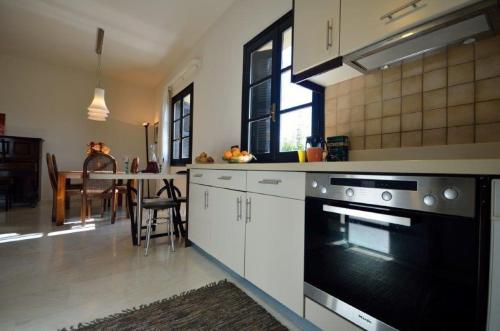 a kitchen with white cabinets and a black oven at Knossos Palace Secluded Villa in Skalánion