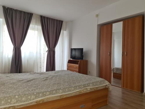a bedroom with a bed and a tv and curtains at Apartament ANNA in Târgovişte