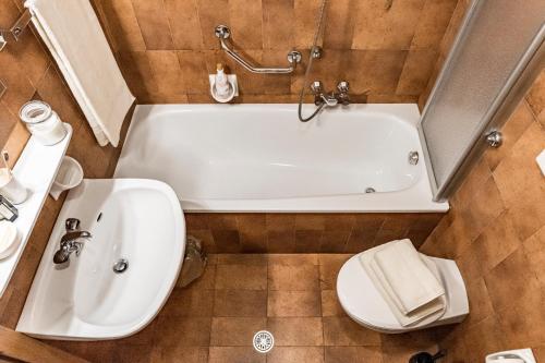 a bathroom with a tub and a toilet and a sink at Residence Greymold in Rifiano