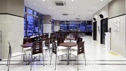 um restaurante com mesas, cadeiras e janelas em Toyoko Inn Shonan Hiratsuka eki Kita guchi No 1 em Hiratsuka