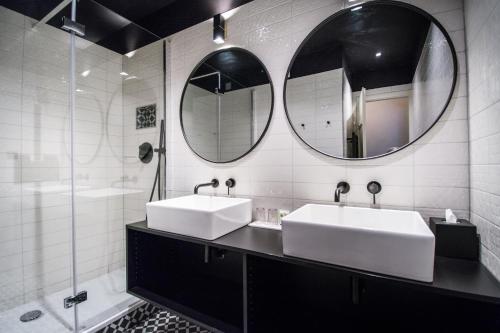 two sinks in a bathroom with two mirrors at Hôtel Restaurant Vaillant proche Europapark Rulantica in Sélestat