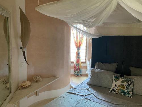 a bedroom with a canopy bed and a window at Watamu Shell House in Watamu