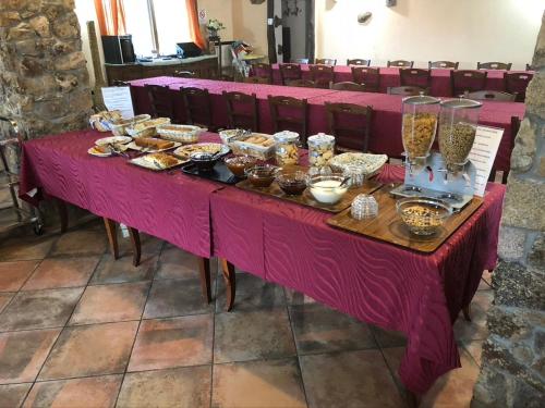 una larga mesa rosa con un montón de comida. en Agriturismo Rocce Bianche - Bungalows en Arbus