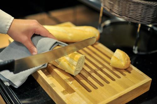 a person cutting bread on a cutting board with a knife at Melia Athens in Athens