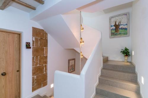 a staircase in a house with white walls and a stone wall at Hotel S'Antiga Adults Only in Es Mercadal