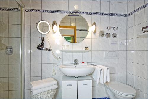 a bathroom with a sink and a toilet and a mirror at Gästehaus Lärcheck Berchtesgaden FeWo Gipfelzauber in Berchtesgaden