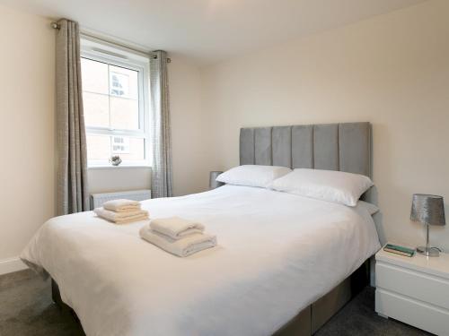 una camera da letto con un grande letto bianco con asciugamani di Pass the Keys Stunning 2 bed Apartment with free onsite parking a Nottingham