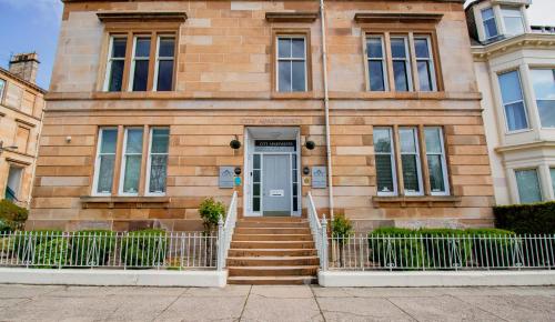 a brick house with a blue door and stairs at City Apartments in Glasgow