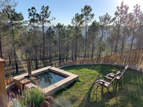 a garden with two chairs and a pool in the grass at Krakeelpoort Herberg in Botrivier