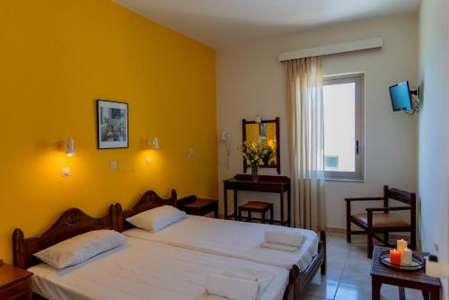 a bedroom with two beds and a yellow wall at Almyra Apartments & Suites in Sfakaki