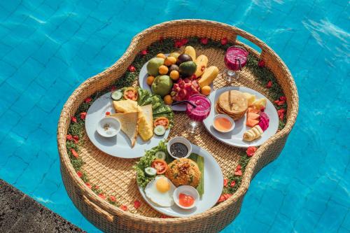 ein Tablett mit Frühstücksspeisen neben dem Pool in der Unterkunft Akusara Jungle Resort And Spa in Nusa Penida