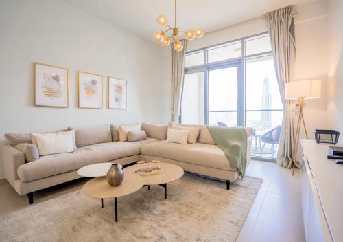 - un salon avec un canapé et deux tables dans l'établissement Nasma Luxury Stays - Bellevue Tower 1, à Dubaï
