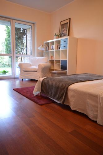 a bedroom with a bed and a chair and a window at Apartament przy Koniu Trojańskim in Luboń