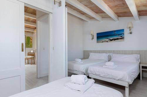 two beds in a room with white walls and wooden ceilings at Rosamar Holidays Apartments in Cala Ratjada
