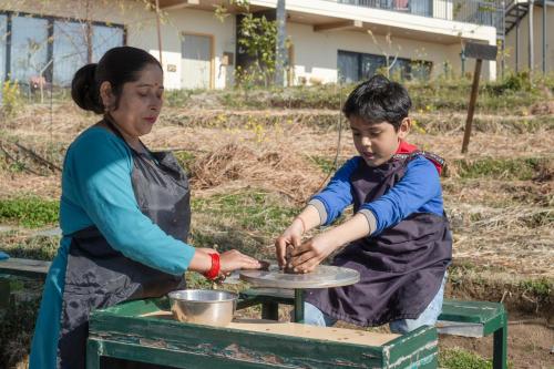 a woman and a boy preparing food on a table at Rakkh Resort, a member of Radisson Individuals Retreats in Pālampur