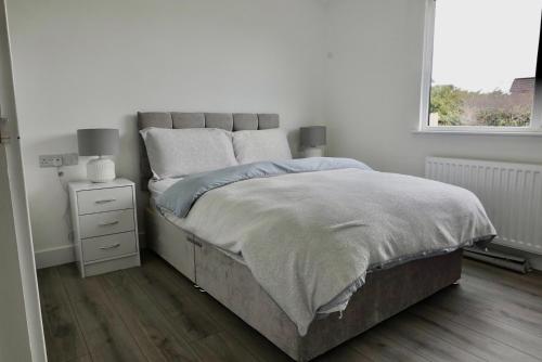 a white bedroom with a bed and a window at Castle View Chalet by Clonlum Cottages in Newry