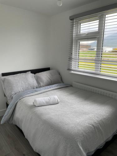 a white bedroom with a large bed with a window at Castle View Chalet by Clonlum Cottages in Newry