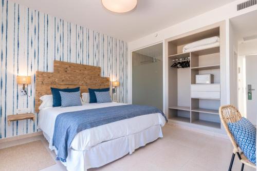 um quarto com uma cama com uma parede listrada em azul e branco em Hotel Playa Santandria Adults Only em Cala Santandria