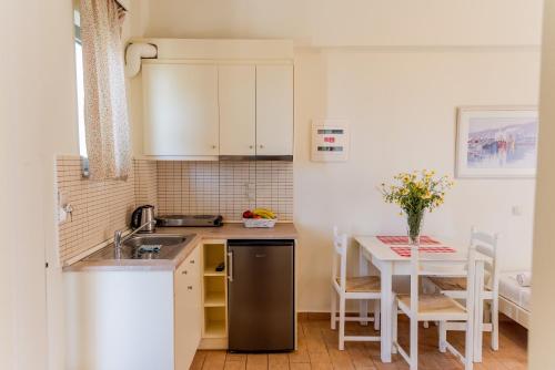 a kitchen with a sink and a table with chairs at Almyra Apartments & Suites in Sfakaki